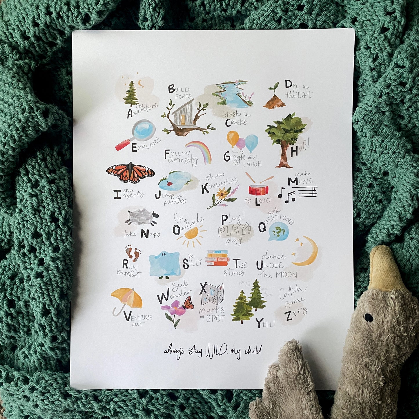 ABCs of Childhood alphabet art print by Stray Folk. laying on baby blanket with a stuffed goose